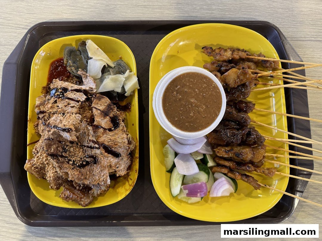 A tray featuring two yellow plates: one with satay skewers and peanut sauce, the other with rojak.