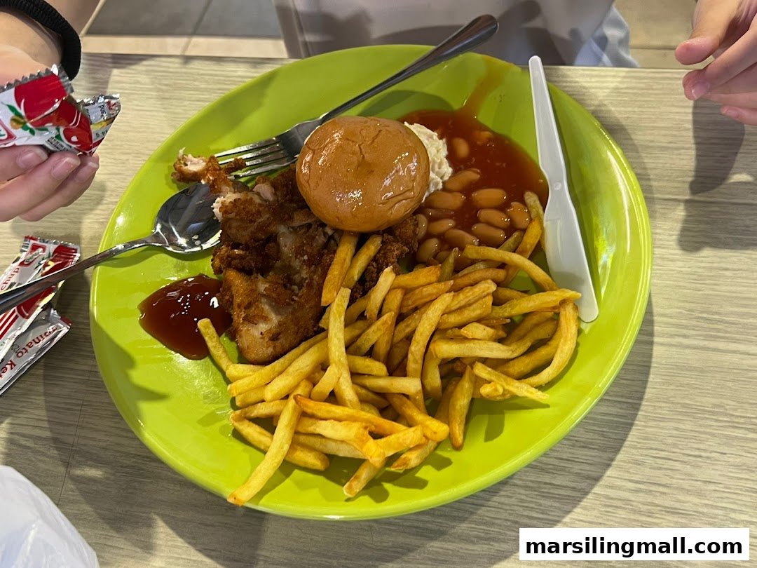 A vibrant green plate holds a hearty meal of fried chicken, golden fries, baked beans, and a bun.