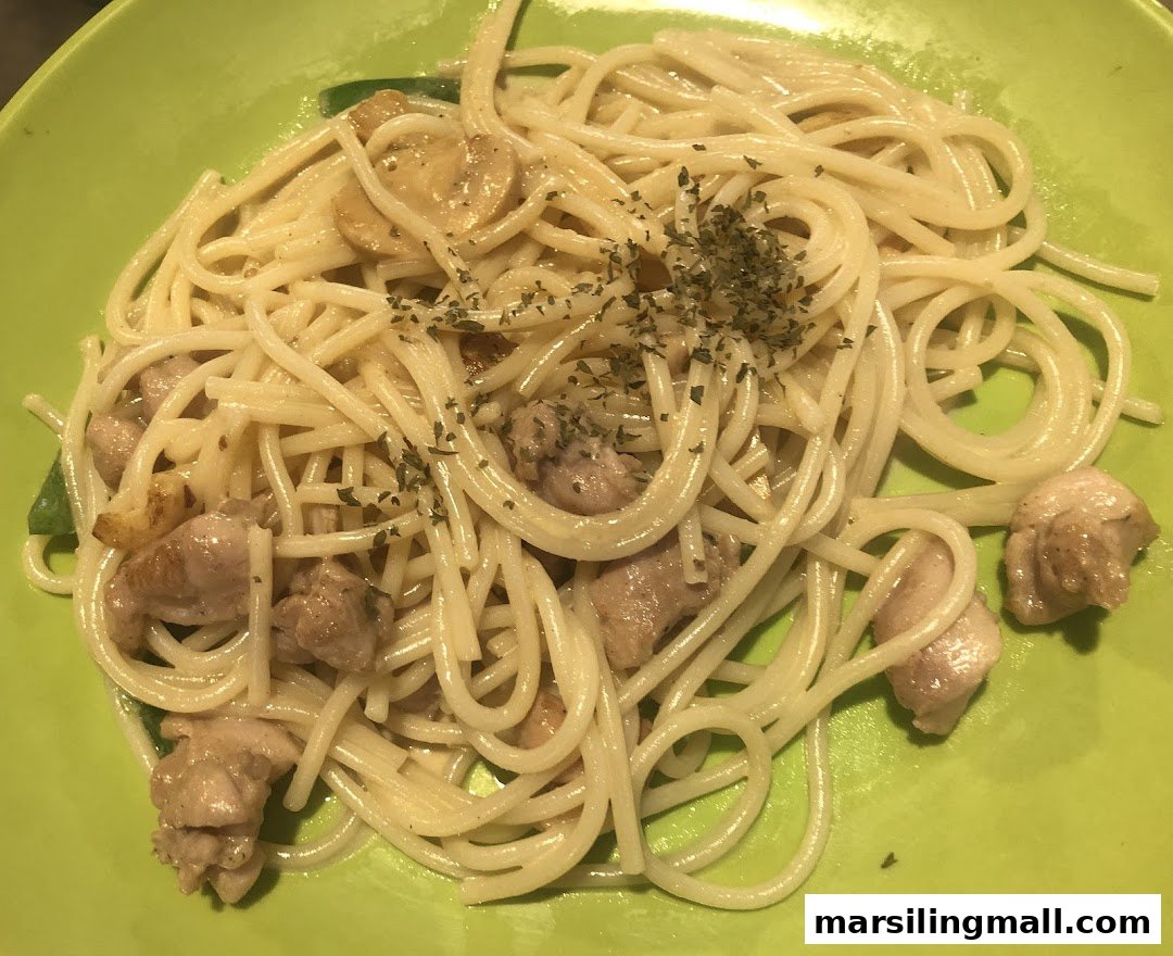 A close-up of spaghetti with chicken, mushrooms, and herbs on a bright green plate.