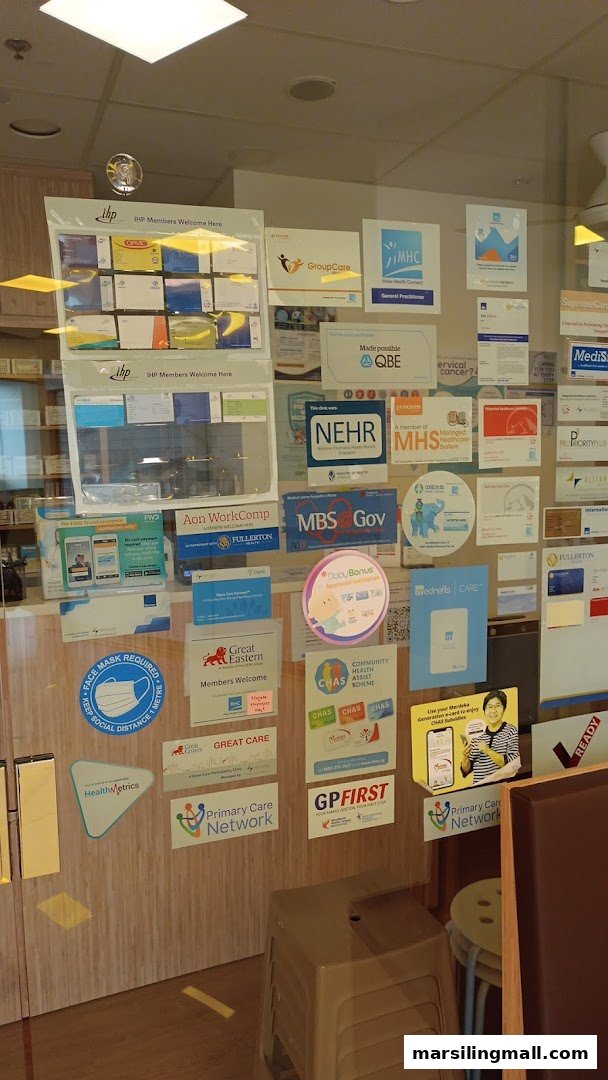 The glass entrance of OneCare Clinic Woodlands, covered with numerous healthcare partnership and affiliation signs.
