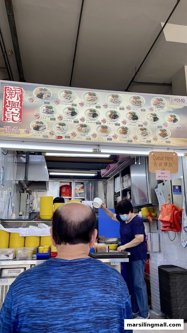 A bustling food stall featuring a large menu board displaying various porridge options.