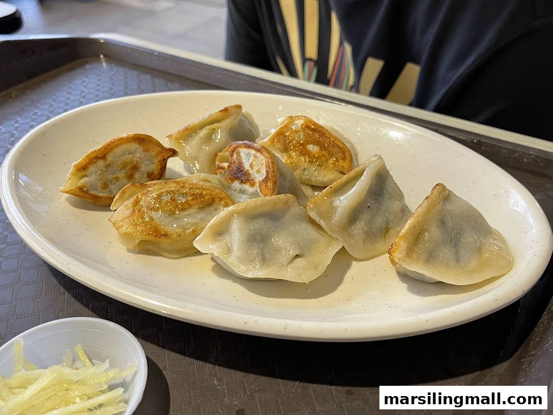 A plate of golden pan-fried dumplings served with shredded ginger.