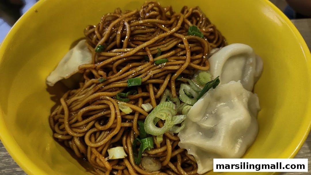 A vibrant yellow bowl filled with savory noodles, garnished with green onions and plump dumplings.