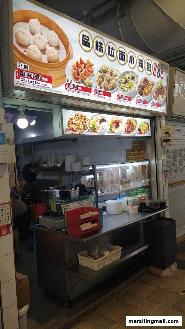 A food stall's illuminated signboard displaying various Chinese dishes like dumplings and noodles with prices.