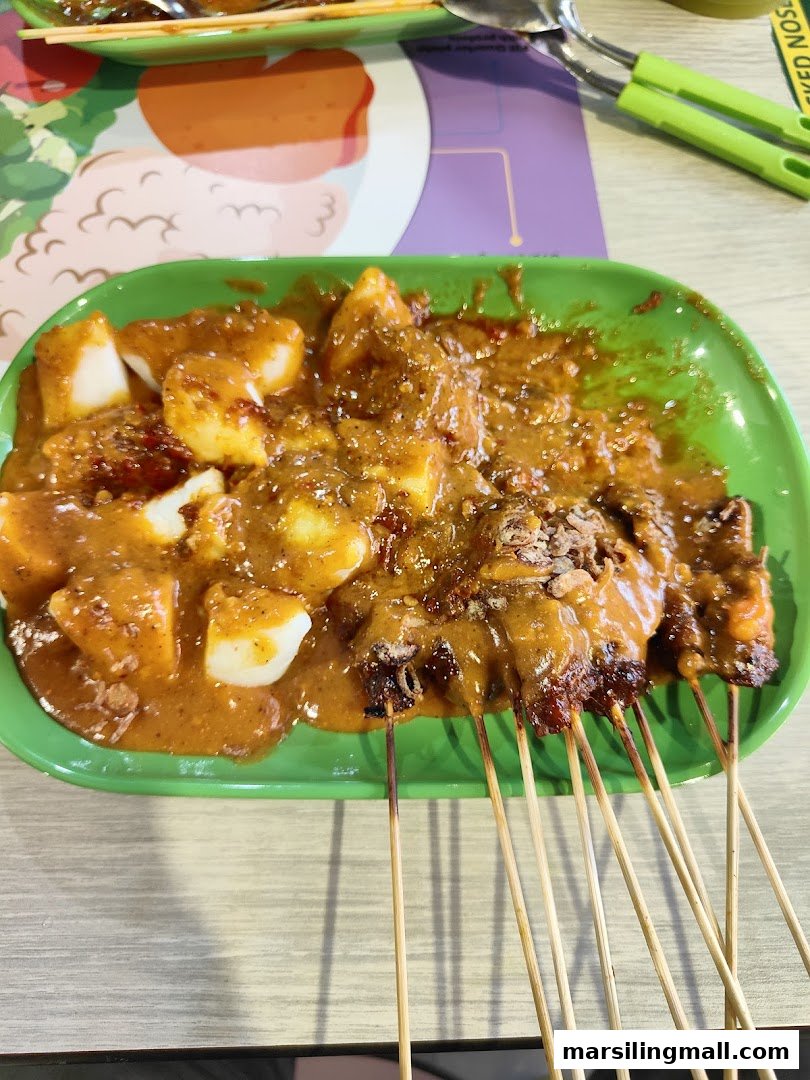 A vibrant green plate filled with delicious satay skewers and rice cakes generously covered in rich peanut sauce.