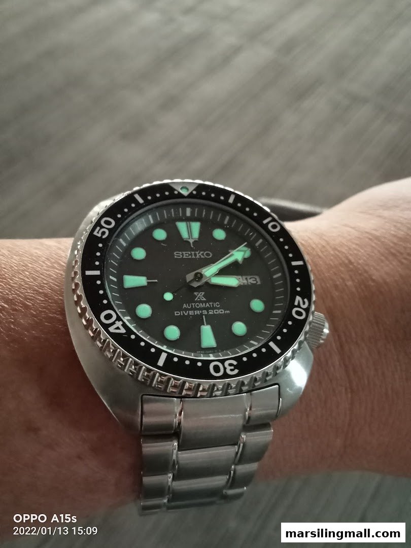 A close-up of a Seiko automatic diver's watch with a metal bracelet on a wrist.