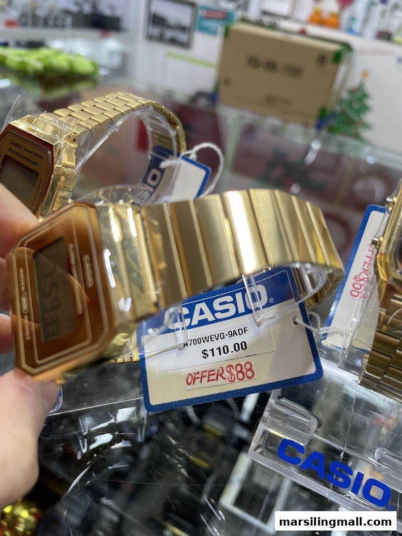 Close-up of gold Casio watches displayed with price tags showing a special offer.