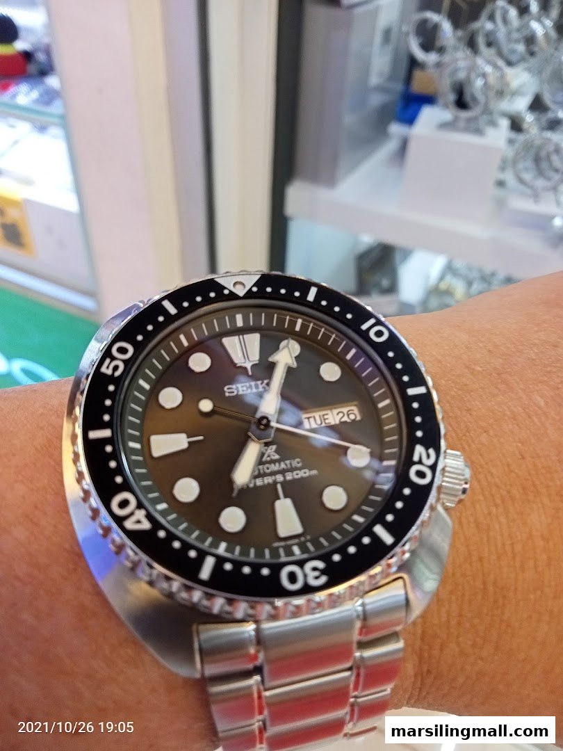 A close-up of a Seiko automatic diver's watch on a wrist, likely inside a watch shop.