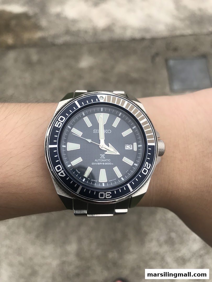 A close-up of a Seiko automatic diver's watch with a blue dial on a person's wrist.