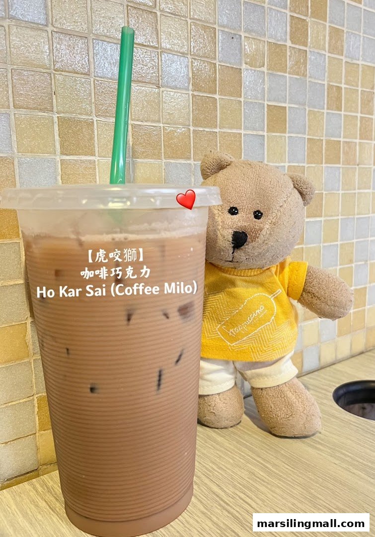 A refreshing iced coffee Milo drink with a cute teddy bear against a tiled wall.