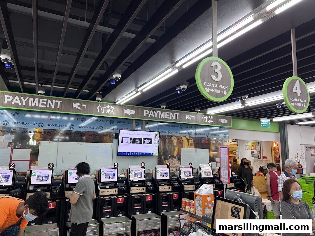 Customers use self-checkout machines at Sheng Siong Supermarket, featuring clear payment signage.