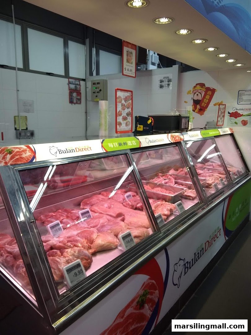 A refrigerated display counter showcasing various fresh meat cuts inside Sheng Siong Supermarket.