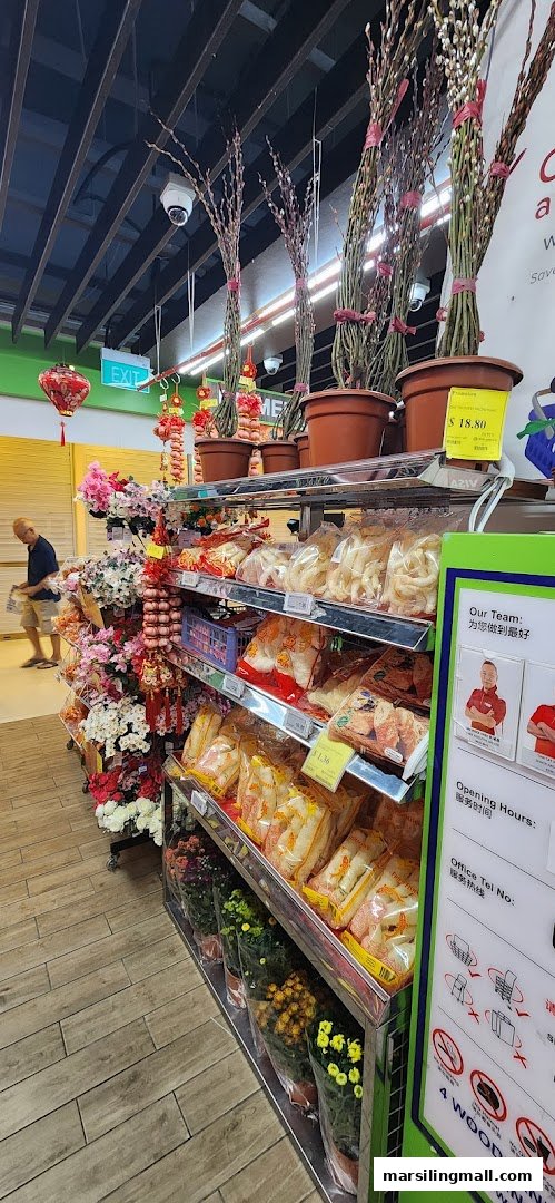 An aisle in Sheng Siong Supermarket featuring festive decorations, fresh flowers, and packaged goods.