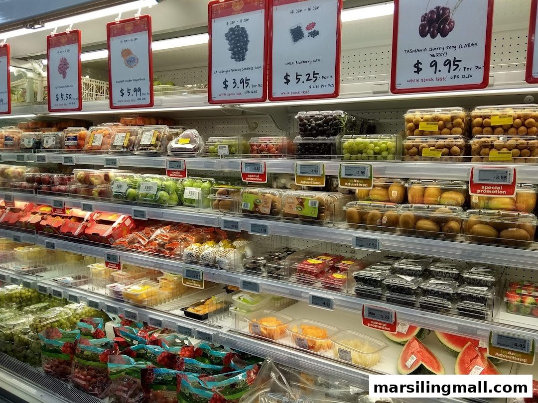 A well-stocked supermarket produce aisle featuring a variety of fresh fruits and clear pricing.