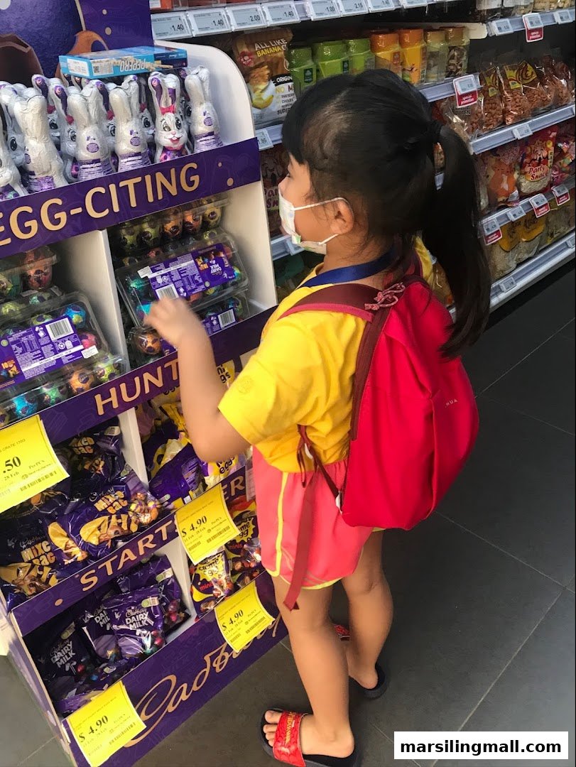 A child in a supermarket aisle, wearing a mask, looking at an Easter chocolate display.