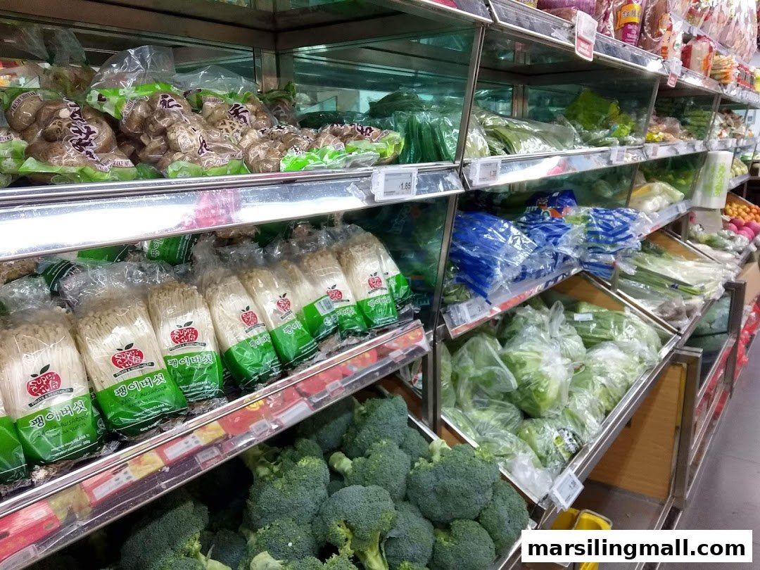 A supermarket aisle displaying various fresh vegetables and mushrooms in packaged and loose forms.