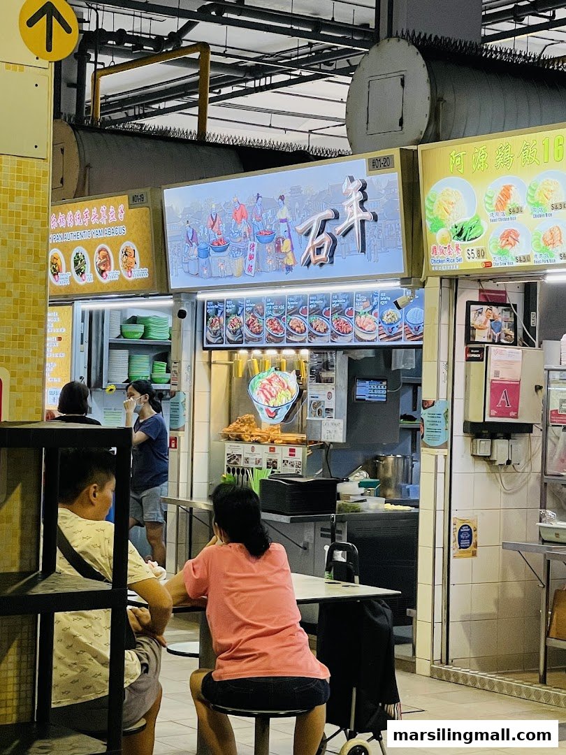 Diners enjoying a meal at a bustling food court with various authentic Asian food stalls.