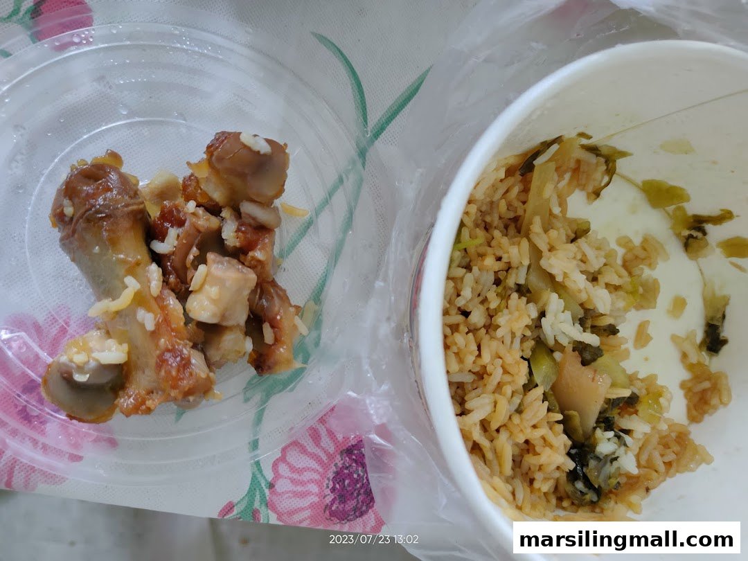 Close-up of tender pig leg pieces and flavorful rice with preserved vegetables, served in takeaway containers.
