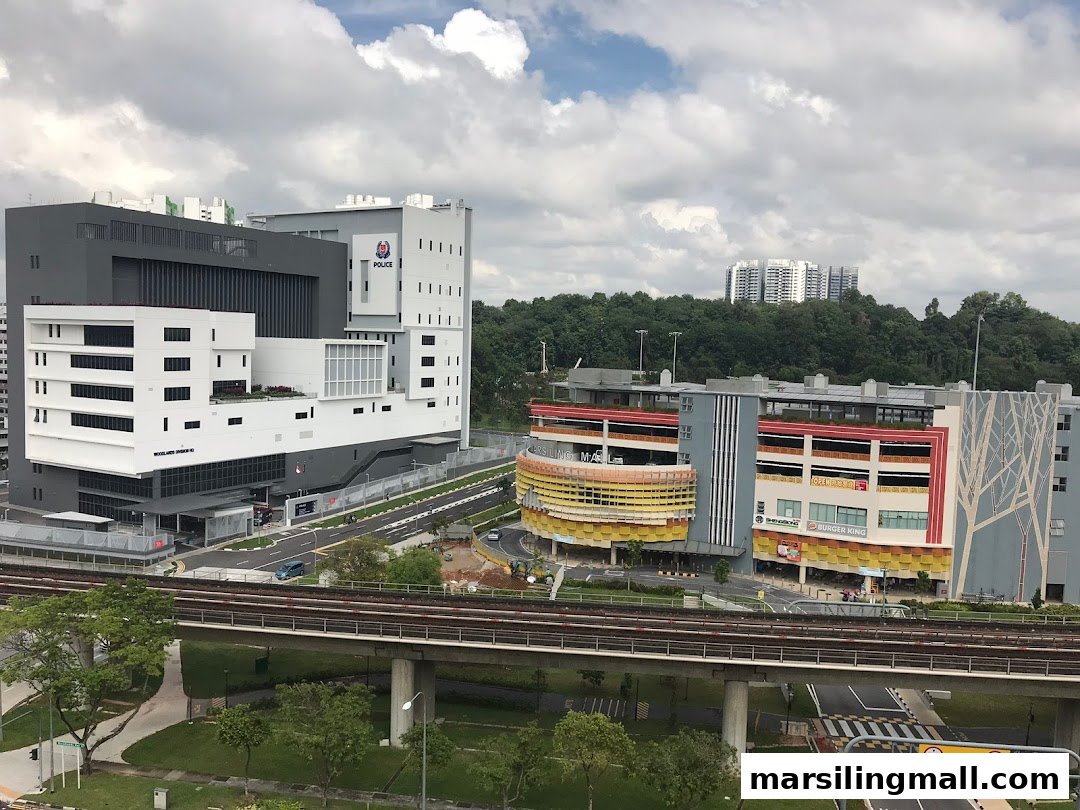 An aerial view of a modern urban landscape featuring multiple buildings, an elevated train track, and lush greenery.