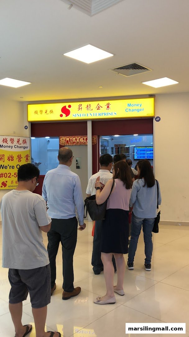 People queueing outside Sineo Enterprises Money Changer, a currency exchange shop.