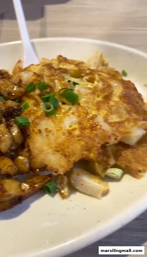 A close-up of a plate of fried carrot cake with egg and chopped spring onions.