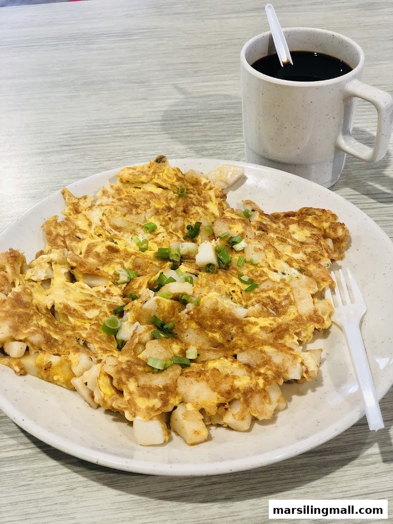 A plate of fried carrot cake with egg and spring onions, served with a cup of coffee.