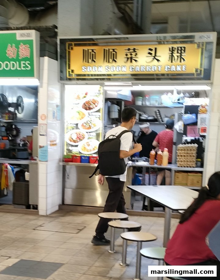 A bustling hawker stall, Soon Soon Carrot Cake, with customers and staff visible.