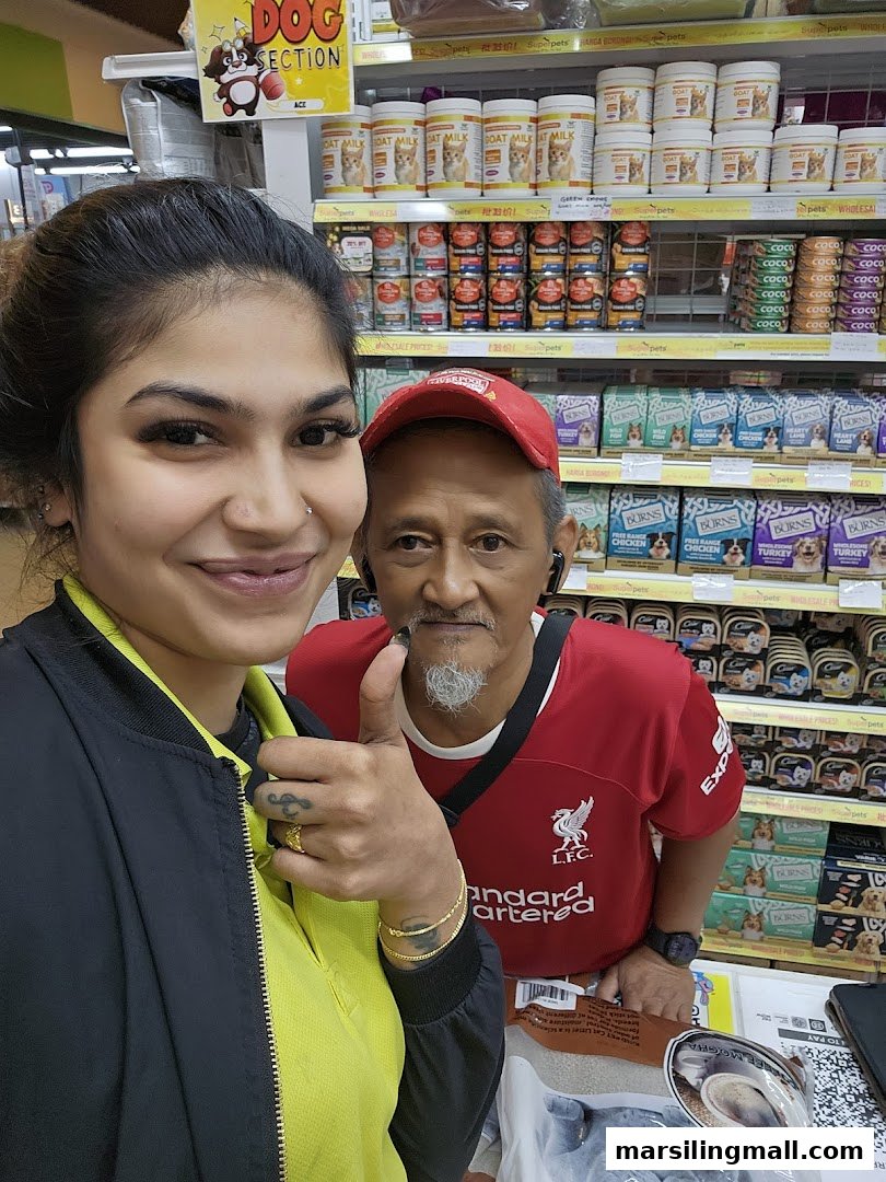 Two happy customers, one giving a thumbs up, inside Superpets Marsiling Mall surrounded by pet products.