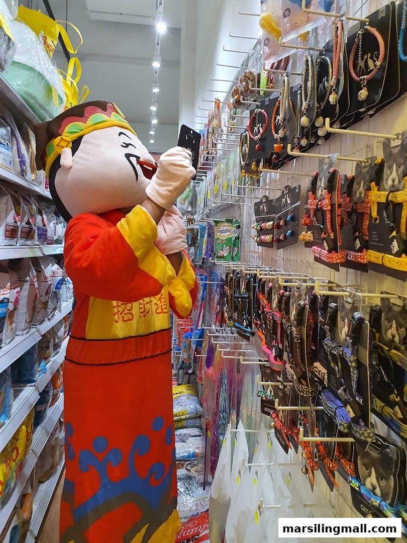 A mascot in a pet shop aisle, surrounded by pet food and accessories.