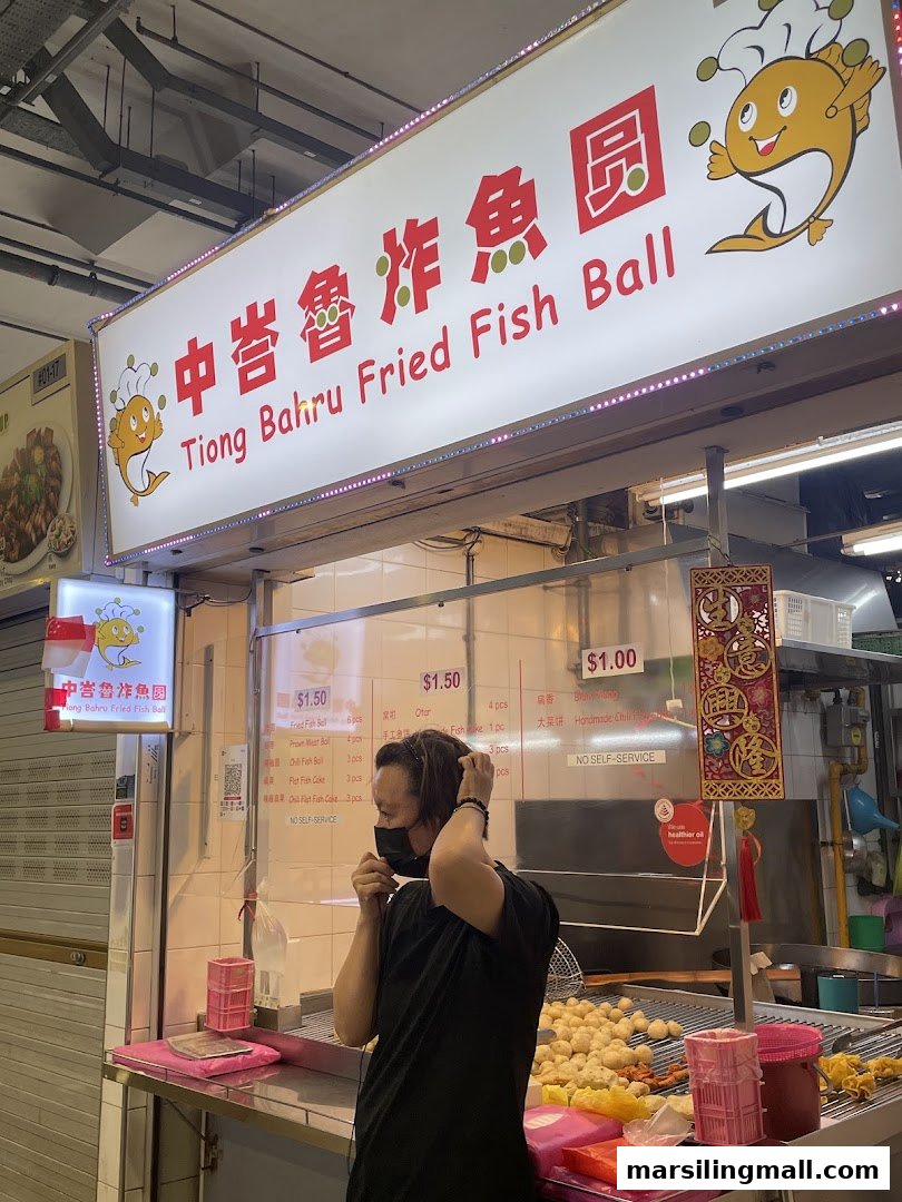A person stands at the counter of Tiong Bahru Fried Fish Ball stall with its signboard.
