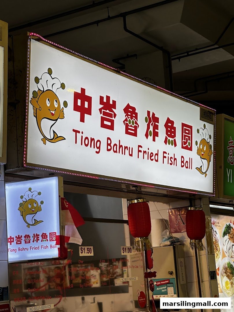 Illuminated sign for Tiong Bahru Fried Fish Ball with shop counter visible.