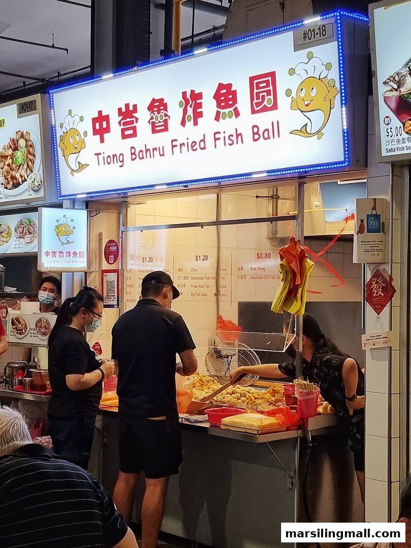 A bustling food stall, 'Tiong Bahru Fried Fish Ball', with staff serving customers and a bright signboard.