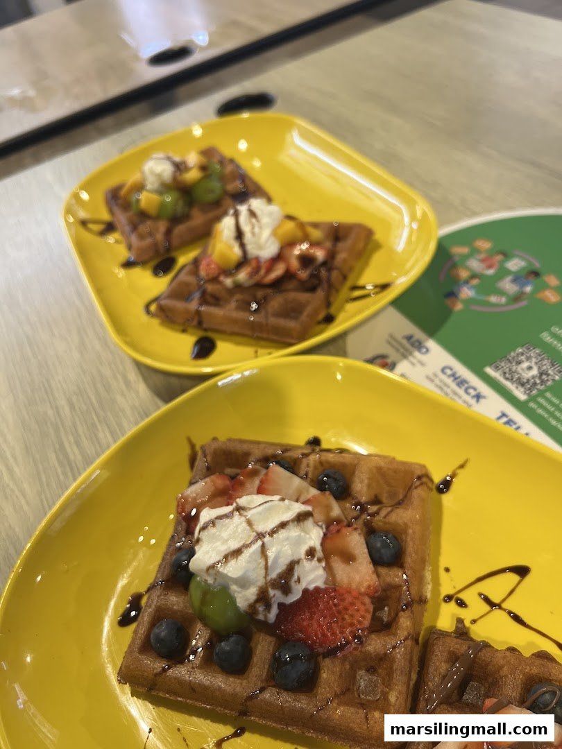 Three delicious waffles topped with fresh fruit, whipped cream, and chocolate drizzle on yellow plates.