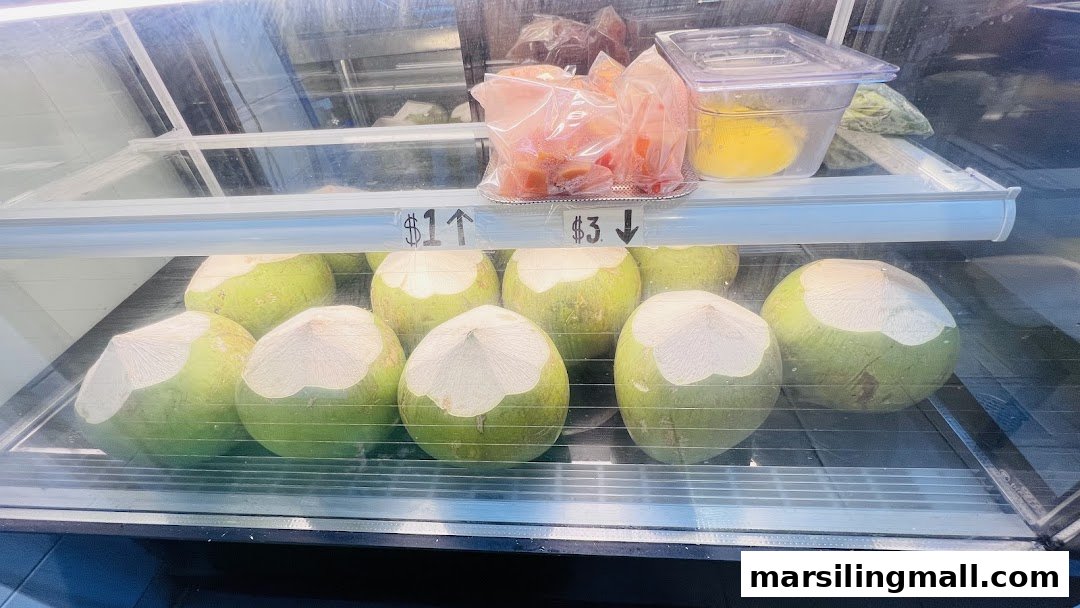A refrigerated display case at WonderFruits showcasing fresh young coconuts and pre-cut tropical fruit.