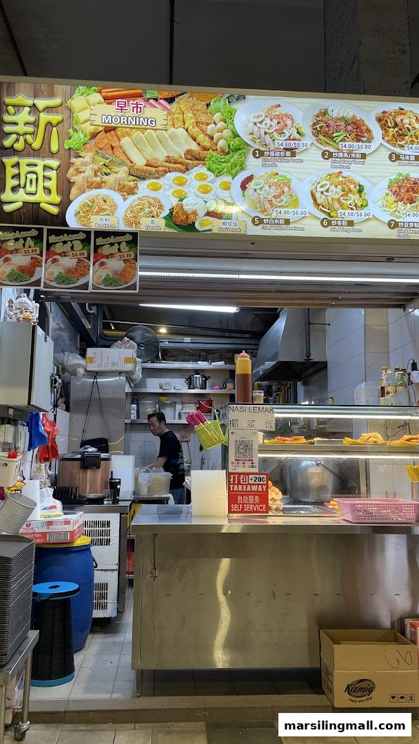 A hawker stall's vibrant menu board showcasing various fried noodle dishes and Nasi Lemak, with a chef working behind the counter.