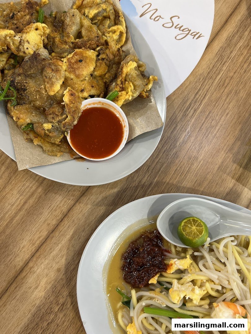 Two plates of delicious food, featuring a fried oyster omelet with chili sauce and a plate of noodles with shrimp.