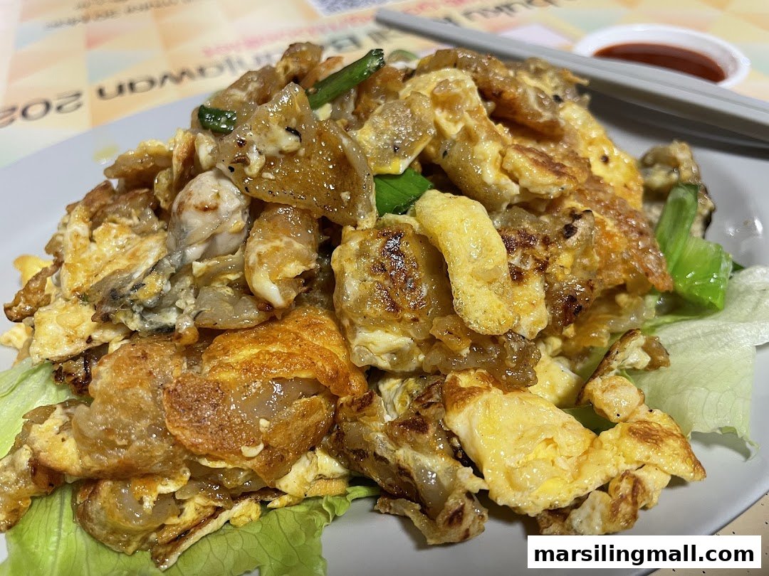 A close-up shot of a plate of golden-brown fried oyster omelette served with fresh lettuce.