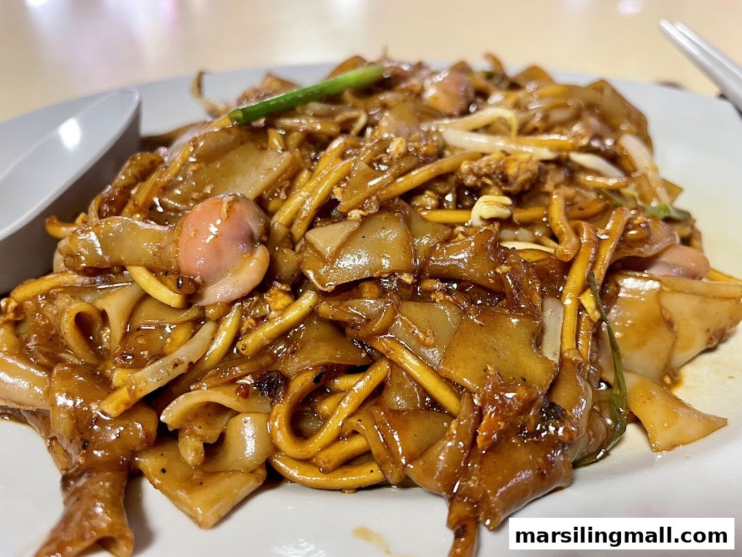 A close-up shot of a delicious plate of stir-fried flat and yellow noodles, garnished with bean sprouts.