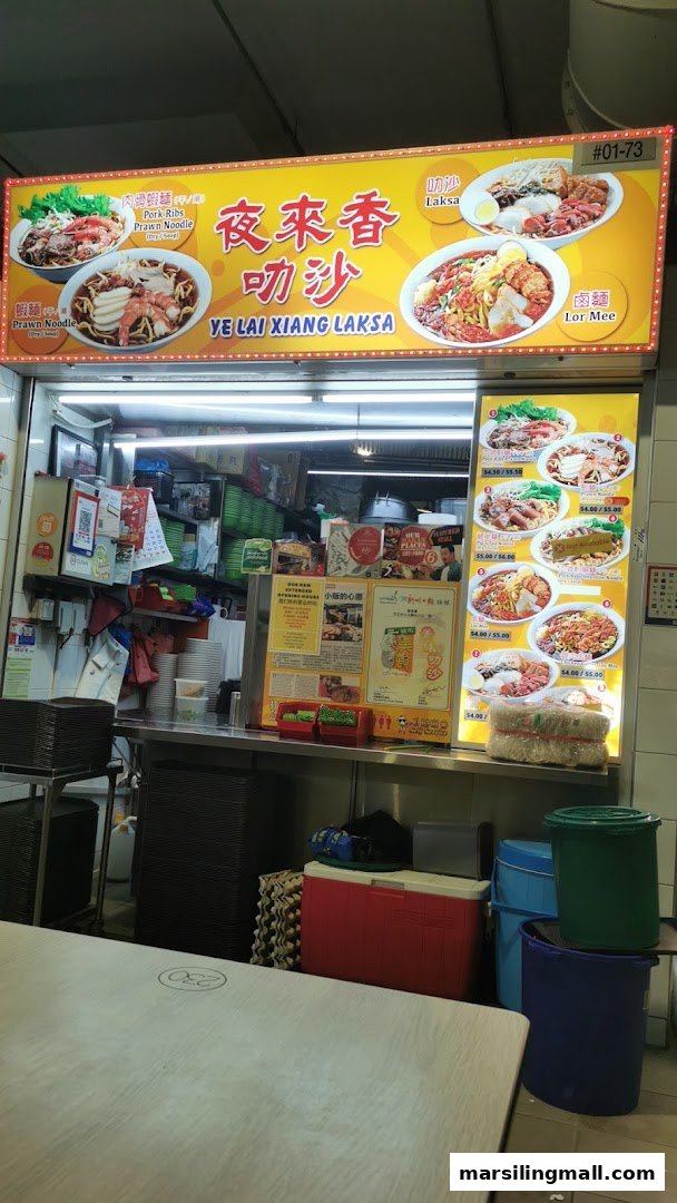 The counter of Ye Lai Xiang Laksa, featuring illuminated signs displaying various noodle dishes and prices.