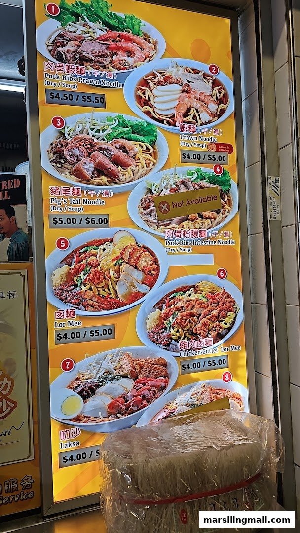A brightly lit menu board displaying various noodle and Laksa dishes with prices and images.