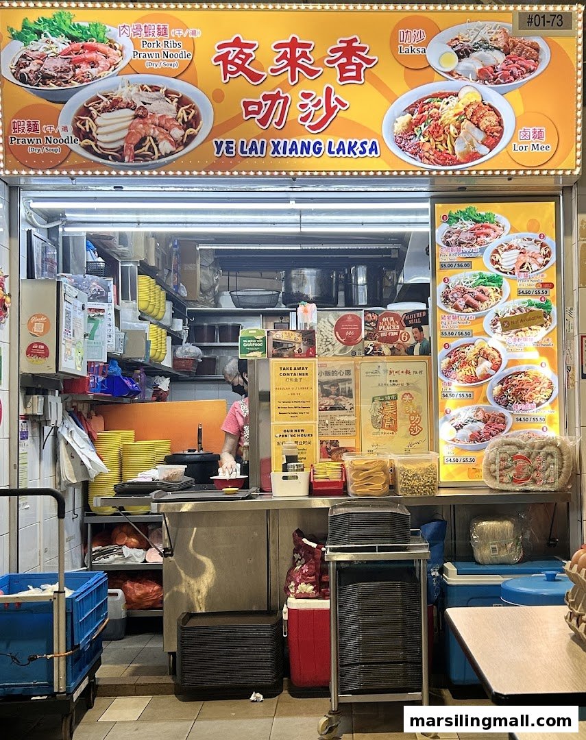 A bustling hawker stall, Ye Lai Xiang Laksa, showcasing its menu and a chef at work.