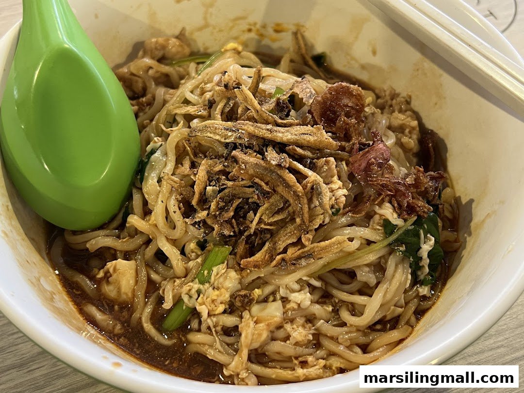 A close-up of a delicious bowl of handmade noodles topped with crispy anchovies and fried shallots.