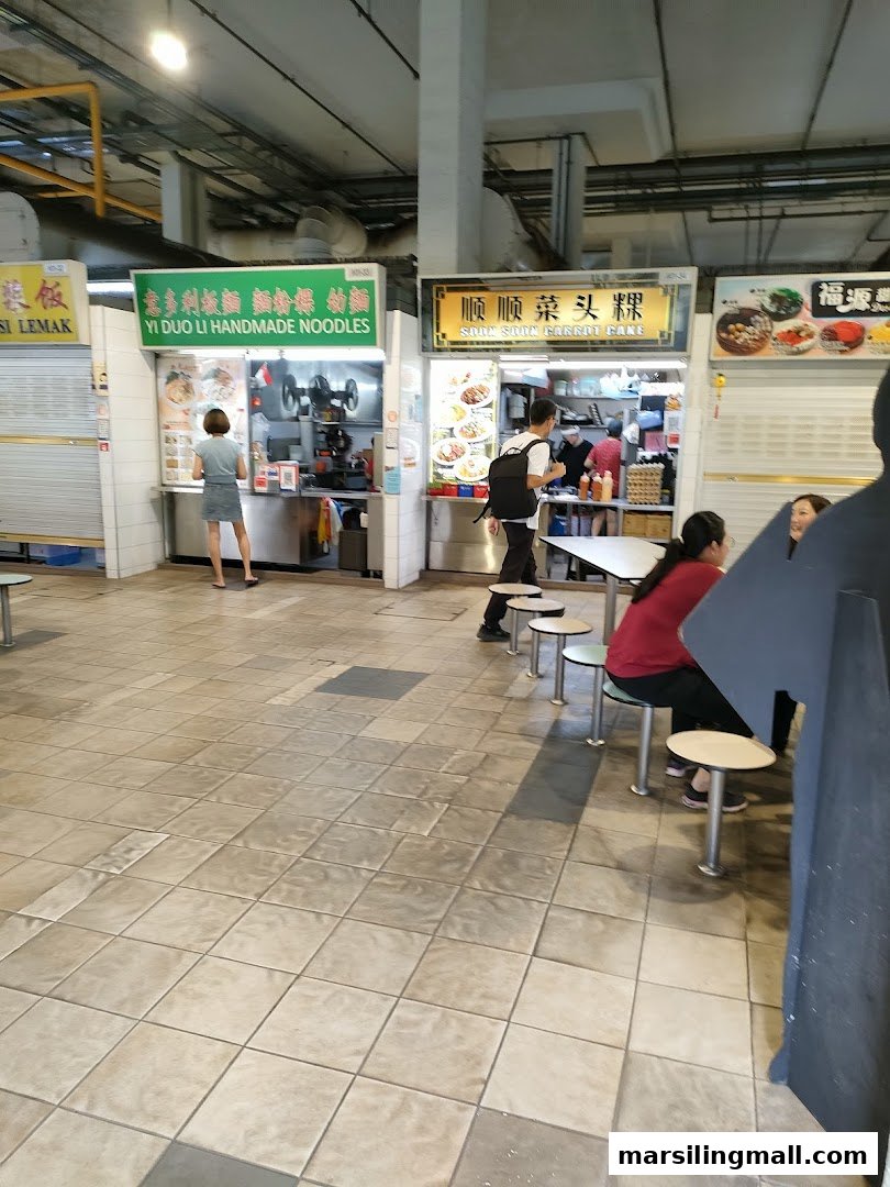 A bustling food stall, 'Yi Duo Li Handmade Noodles,' with customers and staff in a food court.