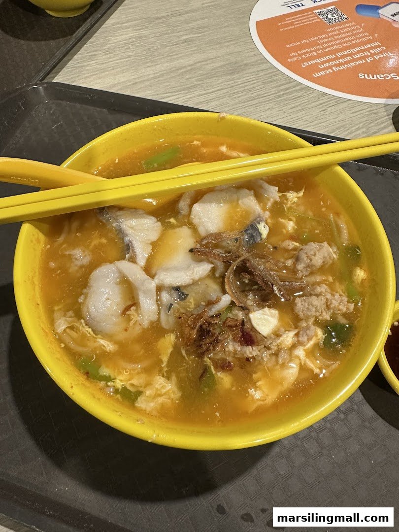 A vibrant bowl of handmade noodles with fish slices, minced meat, and egg in a rich broth.