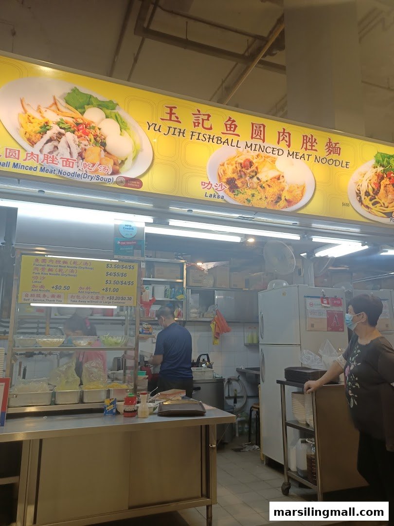 An interior view of Yu Jih Minced Meat Fishball Noodles hawker stall with staff and menu board.