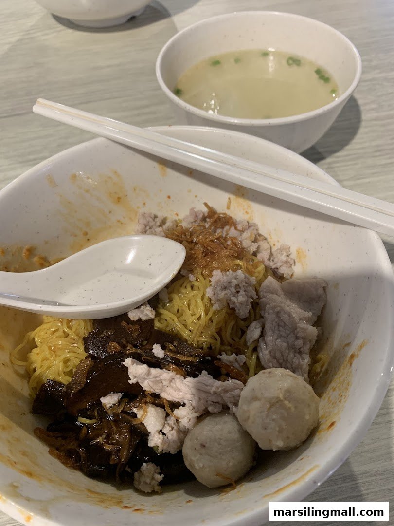 A delicious bowl of minced meat noodles with various toppings and a side of clear soup.