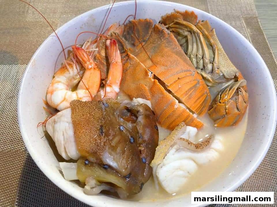 A close-up of a rich seafood soup bowl featuring prawns, slipper lobster, and fish.