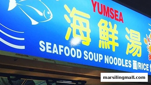 A vibrant blue shop sign for YumSea Seafood Soup, featuring Chinese characters and menu items.