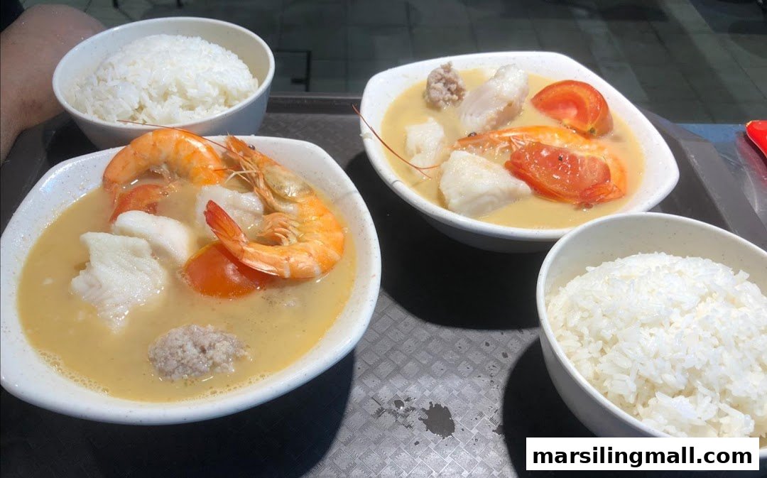 Two bowls of delicious seafood soup with prawns, fish, and tomatoes, served with white rice.
