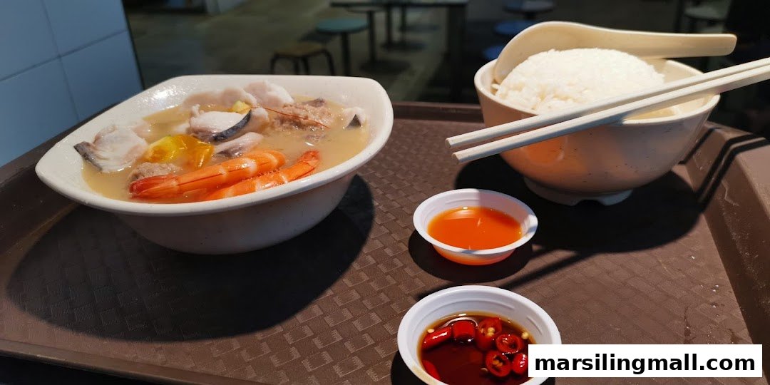 A delicious bowl of seafood soup with fish, prawns, and rice, served with dipping sauces.
